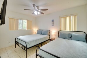 A room with two single beds, a ceiling fan, and two bedside lamps.