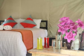 A bedroom with a bed, pillows, a bedside table with drinks, and a vase with flowers. - Rill & River (Nainital)