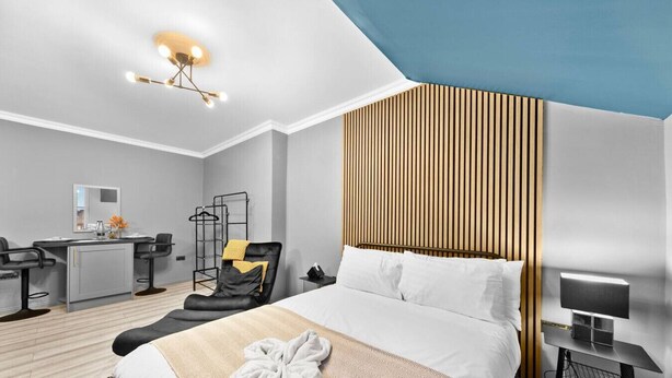 Une chambre d’hôtel moderne équipée d’un lit, d’un bureau, d’une chaise et d’un luminaire suspendu.
