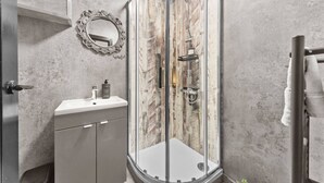 Une salle de bain moderne avec une douche à parois de verre, un meuble-lavabo avec un miroir et un porte-serviettes.