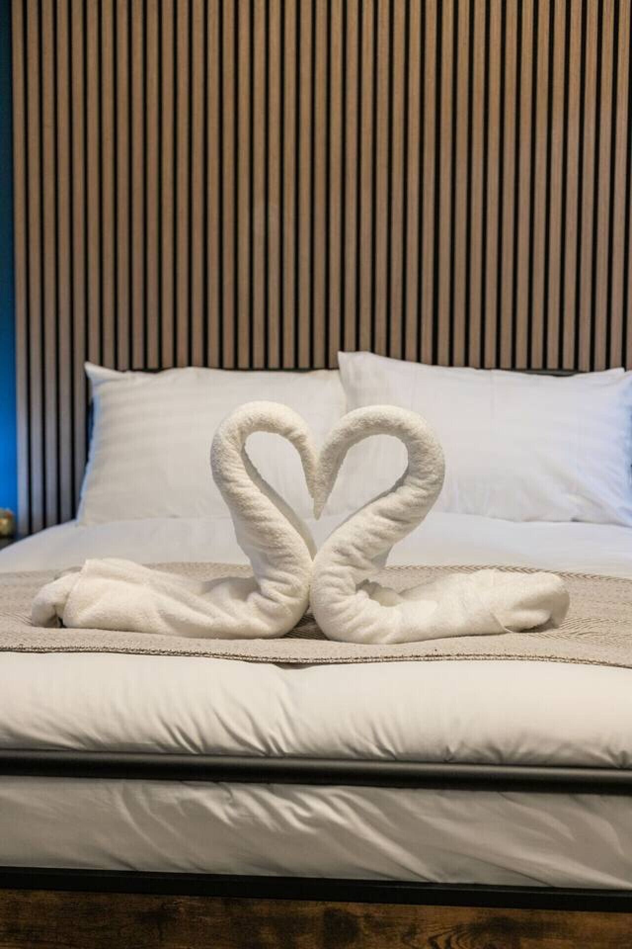 A bed with a heart-shaped towel arrangement.