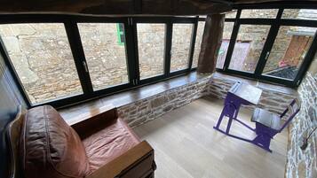 Una habitación acogedora con pared de piedra, banco de madera y una mesa con sillas.