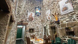 Un comedor rústico con paredes de piedra, una mesa y sillas de madera, un farol colgante y una ventana con vistas.