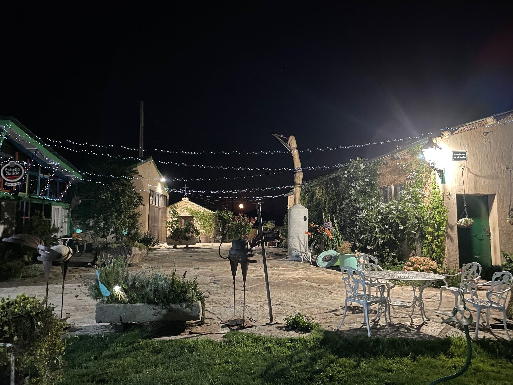 A courtyard with stone flooring, outdoor seating, and string lights.