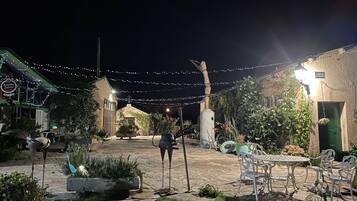 A courtyard with stone flooring, outdoor seating, and string lights.
