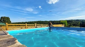 Una piscina con agua azul cristalina, rodeada por una cerca de madera y un suelo de piedra.