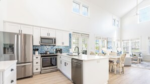 Une cuisine moderne avec des meubles blancs, des appareils en acier inoxydable et un dosseret de carrelage bleu.