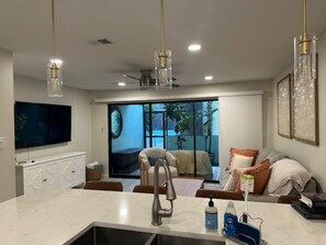 A modern kitchen with a marble countertop, a built-in sink, and pendant lighting.