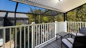 Une terrasse extérieure couverte, dotée d’une balustrade blanche, d’une table et de chaises.