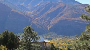 Un paysage de montagne avec une maison au premier plan et un ciel dégagé.