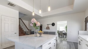 A modern kitchen with a large island, white cabinetry, and pendant lighting. - Chic Cozy Home - Perfect Southern California Getaway (Rosemead)