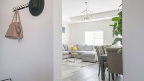 A modern living room with a grey sofa, a small round table, and a dining area with chairs. - Chic Cozy Home - Perfect Southern California Getaway (Rosemead)