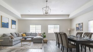 A spacious living room with a gray sofa, a coffee table, and a dining area with a dark wooden table and chairs. - Chic Cozy Home - Perfect Southern California Getaway (Rosemead)