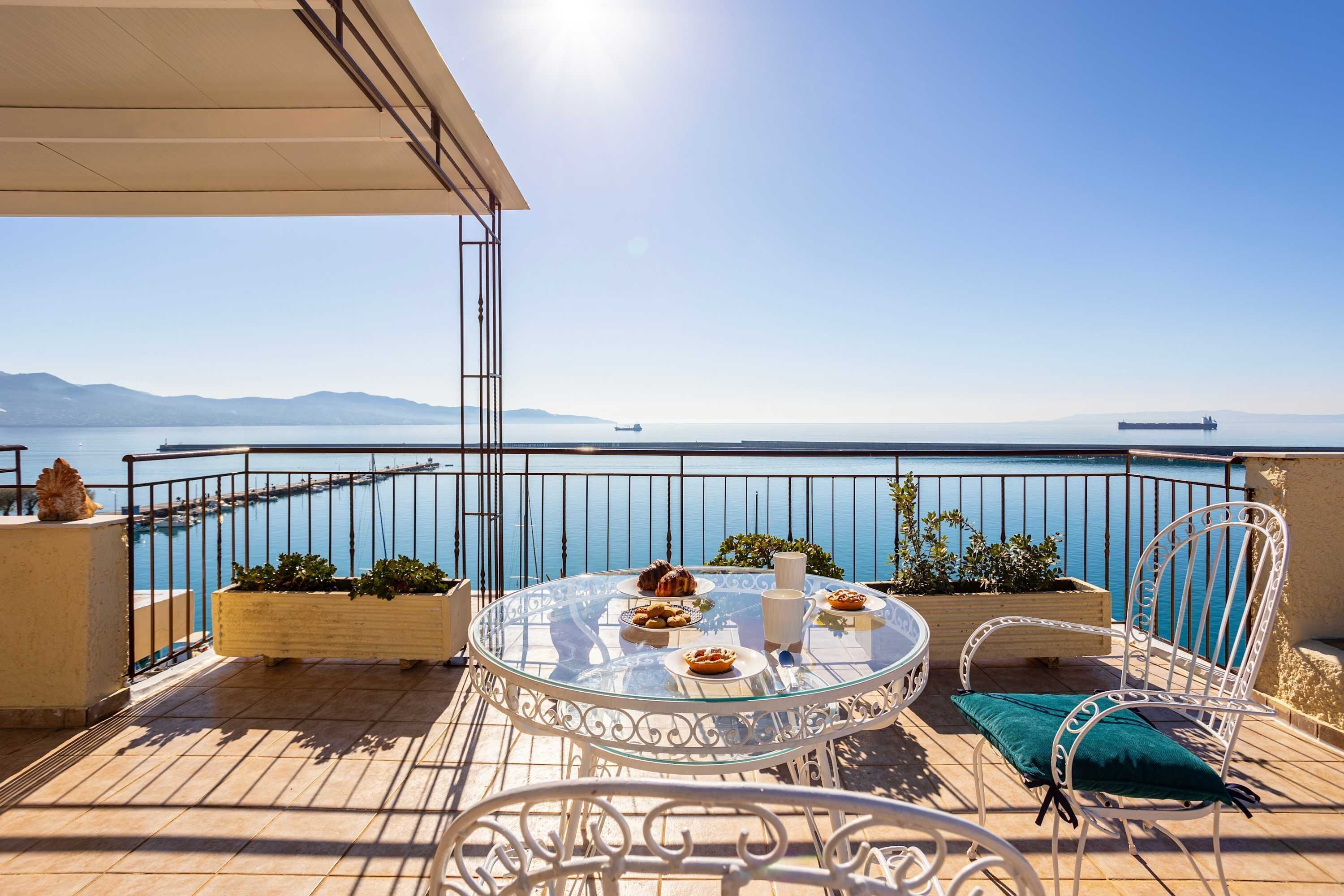 A round glass table with chairs and a view of the sea.