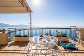 A round glass table with chairs and a view of the sea.
