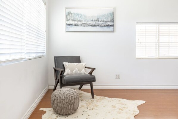 A room with a chair, a rug, and a painting on the wall. - Charming Spacious Home - Modern Comforts Prime Location (Rosemead)