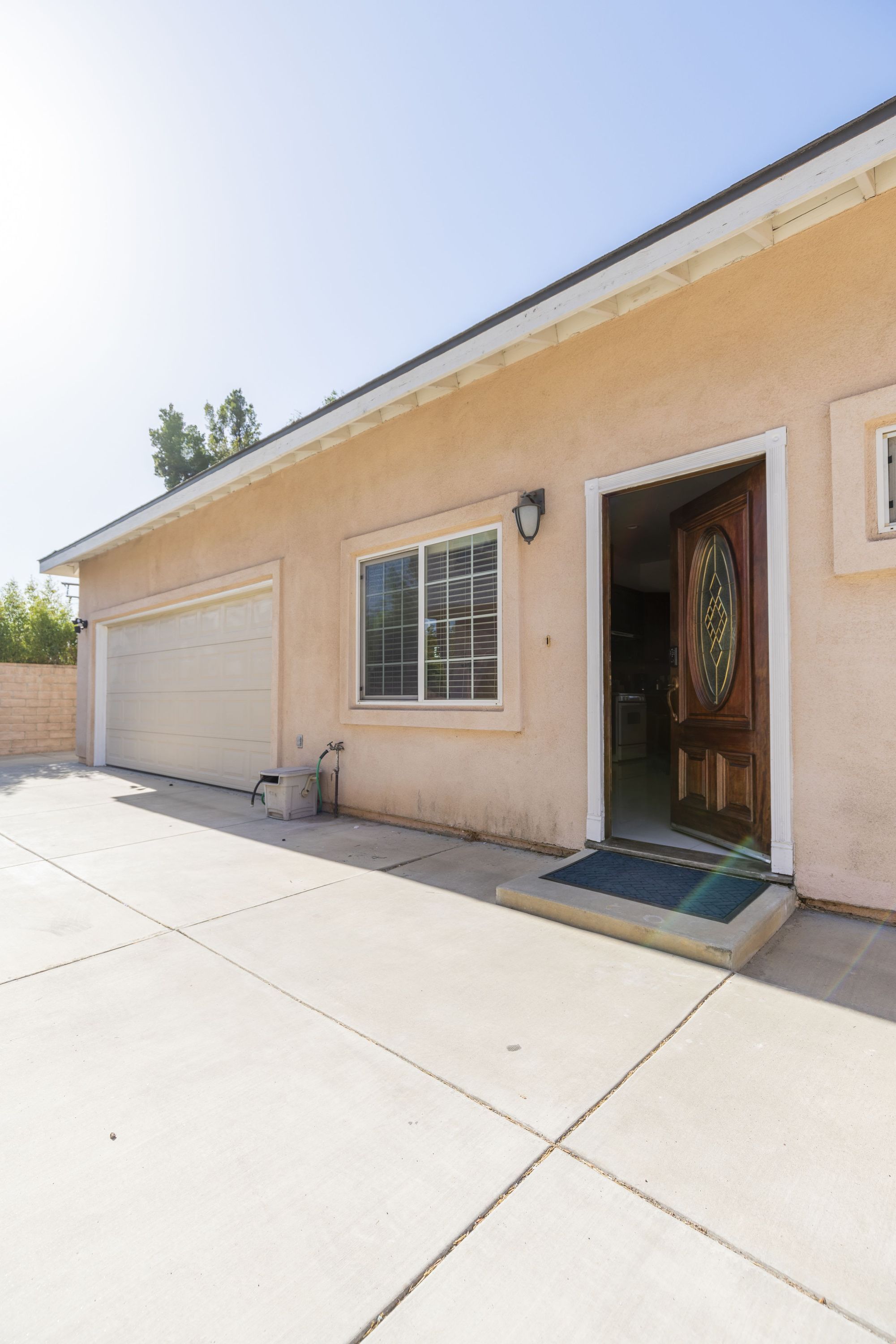 A single-story building with a garage door, a front door with a decorative panel, and a window with a grid pattern.