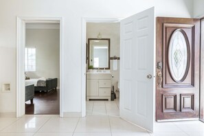 Une chambre d’hôtel avec un lit, une salle de bain dotée d’un miroir et d’un lavabo, et une porte en bois.