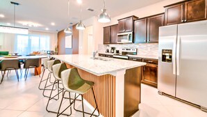 A modern kitchen with a central island, stainless steel appliances, and bar stools. - 16239 7BR Stunning Home For Your Family Vacation (Clermont)