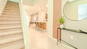 A modern interior with a staircase, a kitchen area, and a bar with stools. - 16239 7BR Stunning Home For Your Family Vacation (Clermont)