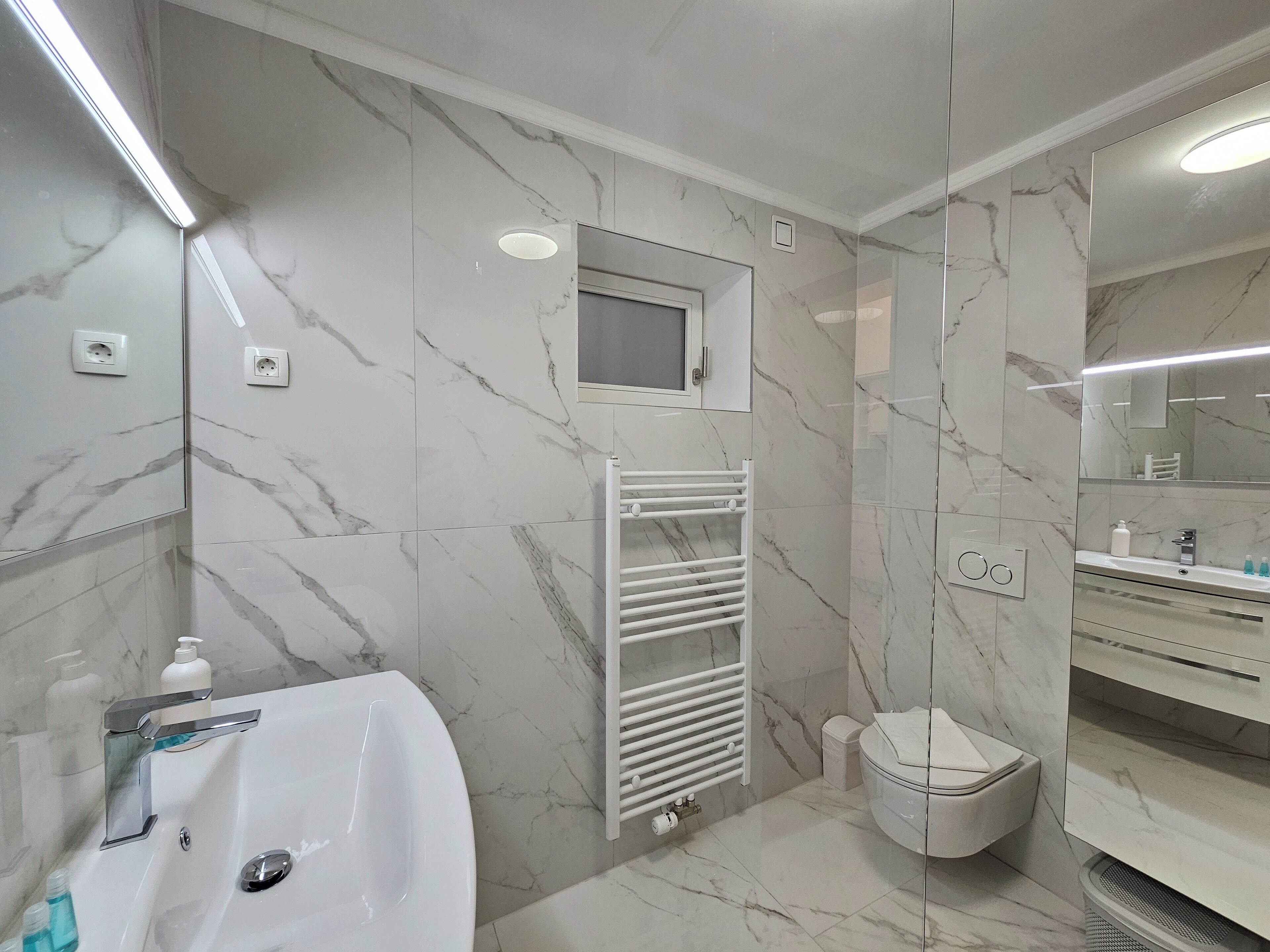 Une salle de bain moderne avec un lavabo blanc, un miroir et des toilettes.
