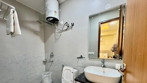 A bathroom with a toilet, bidet, sink, and a towel rack. - Hotel Akshay (Gurugram)