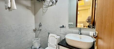 Casa de banho com sanita, bidé, lavatório e porta-toalhas.