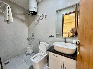 Casa de banho com sanita, bidé, lavatório e porta-toalhas.