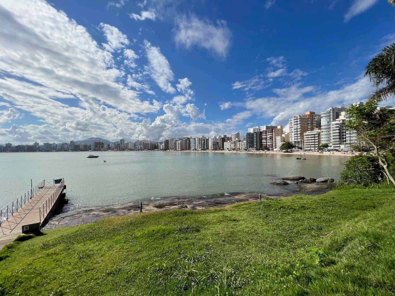 Un paisaje urbano costero con un puerto deportivo, un muelle y edificios altos.