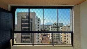 Une fenêtre ornée d’une grille métallique, donnant sur un paysage urbain composé de différents bâtiments.
