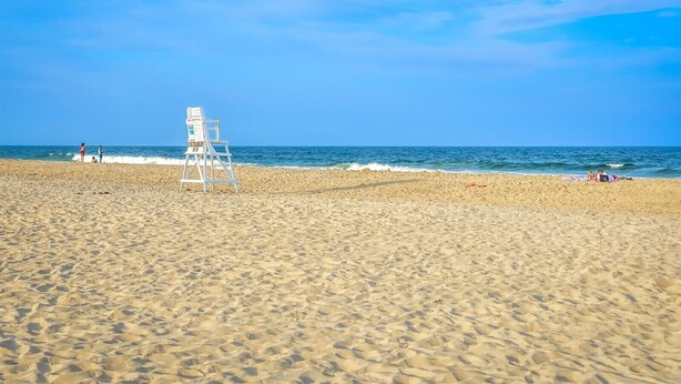 A beach with a lifeguard stand and a clear blue sky. - Jetty's Break-Beautiful 3 Bedroom Condo steps from the beach! (Ocean City)