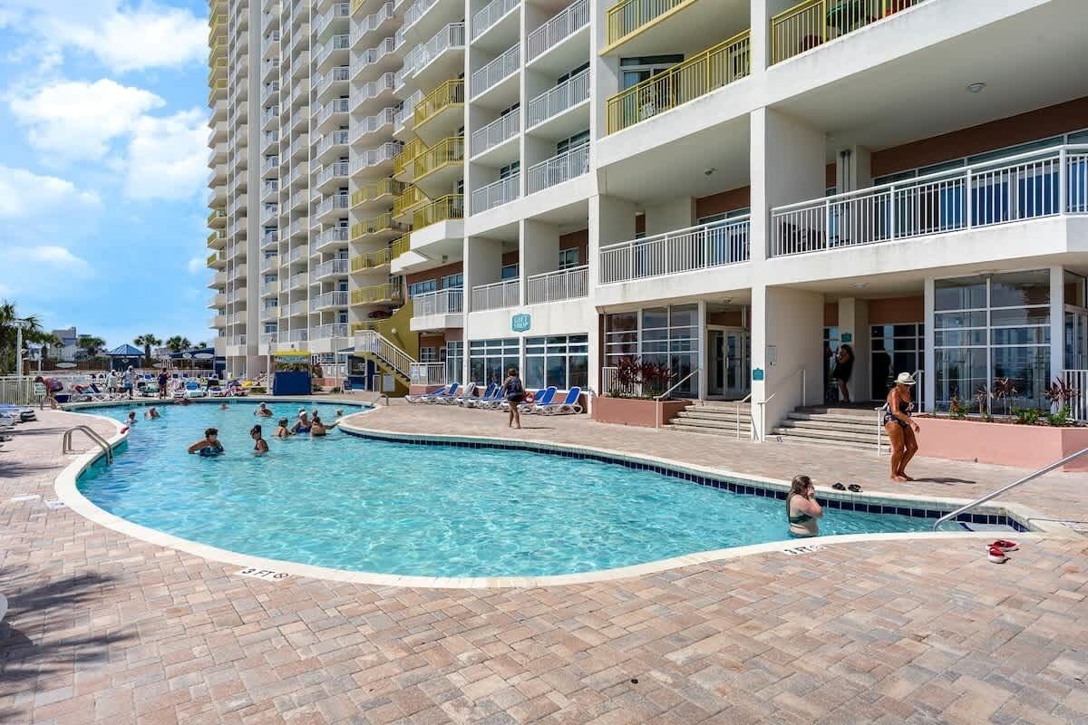 A swimming pool surrounded by a multi-story hotel with balconies and a covered walkway.
