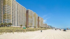 A beachfront hotel with multiple high-rise buildings, a sandy beach, and a clear blue sky. - Luxury Beachfront Resort Condo (Myrtle Beach)