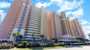 A multi-story hotel with a modern design, featuring a prominent central tower and a series of smaller buildings. - Luxury Beachfront Resort Condo (Myrtle Beach)