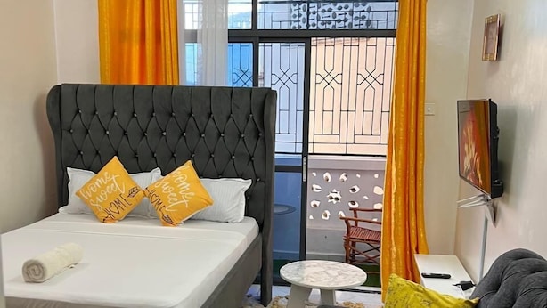 Ein Schlafzimmer mit einem gepolsterten Bett, einer Couch, einem kleinen runden Tisch und einem Fernseher.