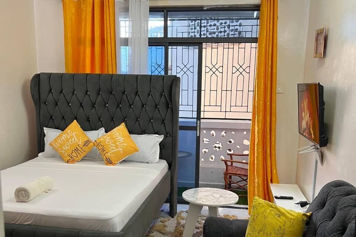 Une chambre avec un lit à capitonnage, un canapé, une petite table ronde et un téléviseur.