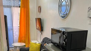 Ein kompakter Wohnbereich mit Sofa, einem kleinen runden Tisch, einer Mikrowelle und einem Kühlschrank.