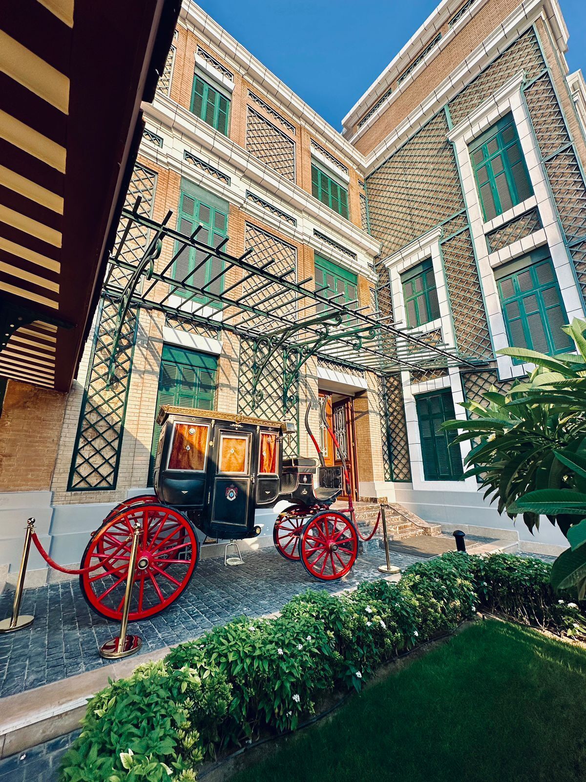Une cour avec un attelage et un bâtiment aux volets verts et à la façade en briques.