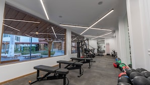 Ein Fitnessstudio mit Trainingsgeräten, Bänken und Blick ins Freie.