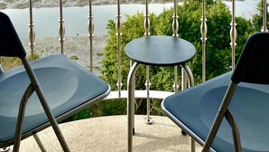 A balcony with two chairs and a table, overlooking a river and distant hills. - The Cliffs - Galician Blue Views (Ortigueira)