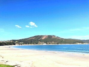 A beach with a mountain in the background, clear skies, and calm waters. - The Cliffs - Galician Blue Views (Ortigueira)