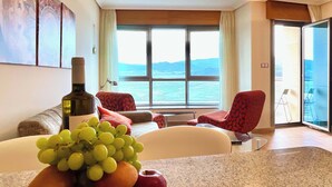 A room with a large window, a bottle of wine, and a fruit bowl. - The Cliffs - Galician Blue Views (Ortigueira)
