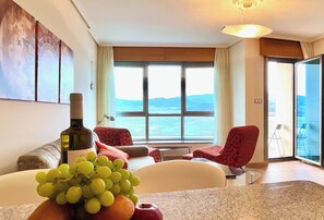 A room with a large window, a bottle of wine, and a fruit bowl. - The Cliffs - Galician Blue Views (Ortigueira)