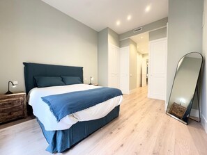 Cozy retreat with a large bed, bedside table, and dresser, plus a full-length mirror.