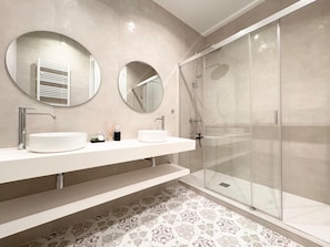 Features two oval-shaped sinks and a high-contrast shower enclosure.