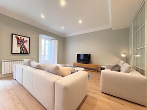 Relax in this stylish living room with a large sofa, flat-screen TV, and floor lamp.