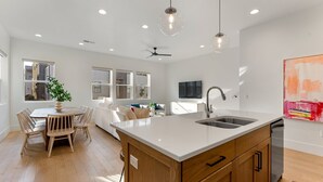 A modern kitchen with a central island, wooden cabinets, and a stainless steel dishwasher.