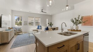 Una cocina moderna con una isla grande, armarios de madera y lavavajillas integrado.