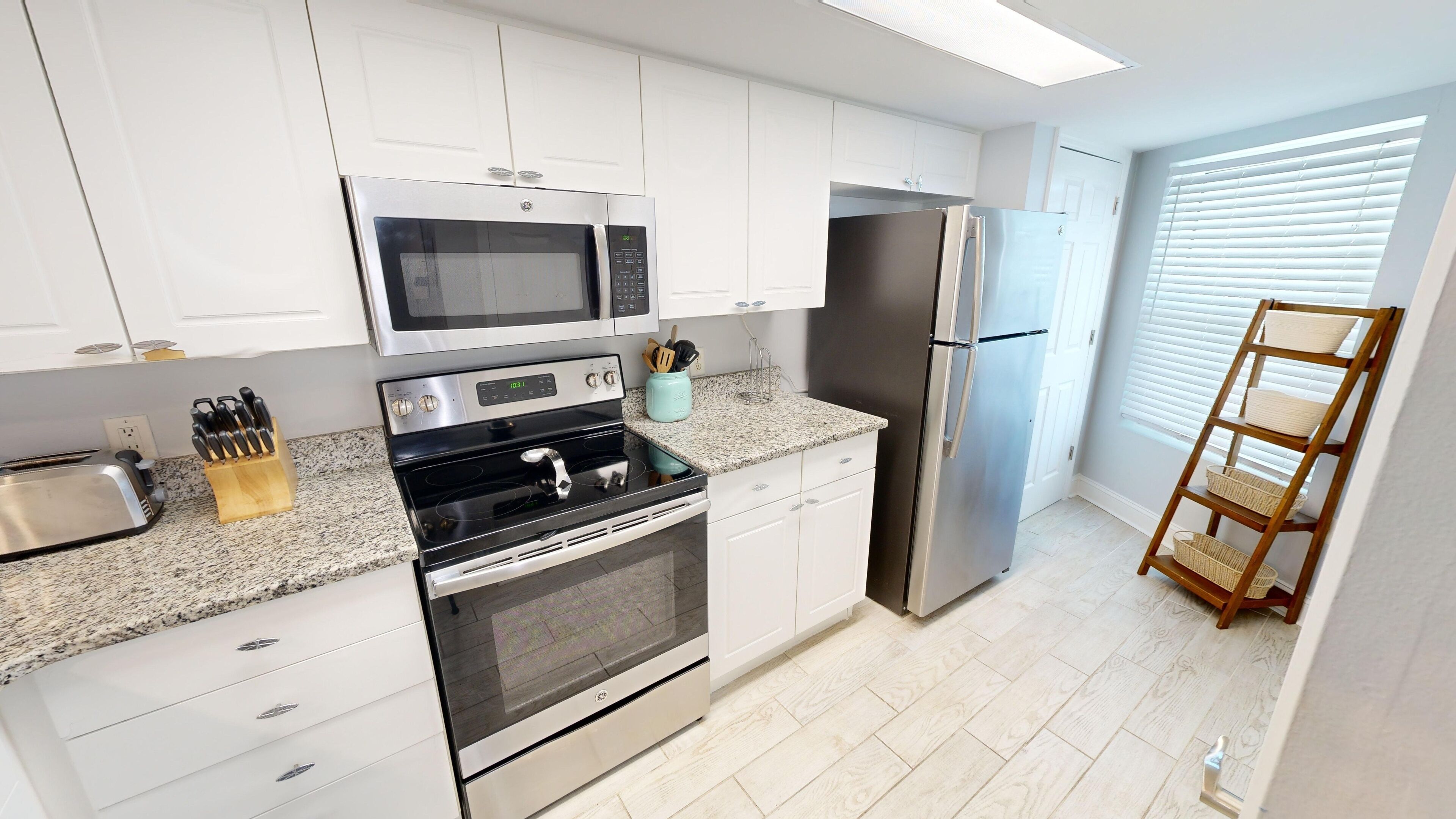 A modern kitchen with white cabinets, stainless steel appliances, a microwave, oven, and refrigerator.