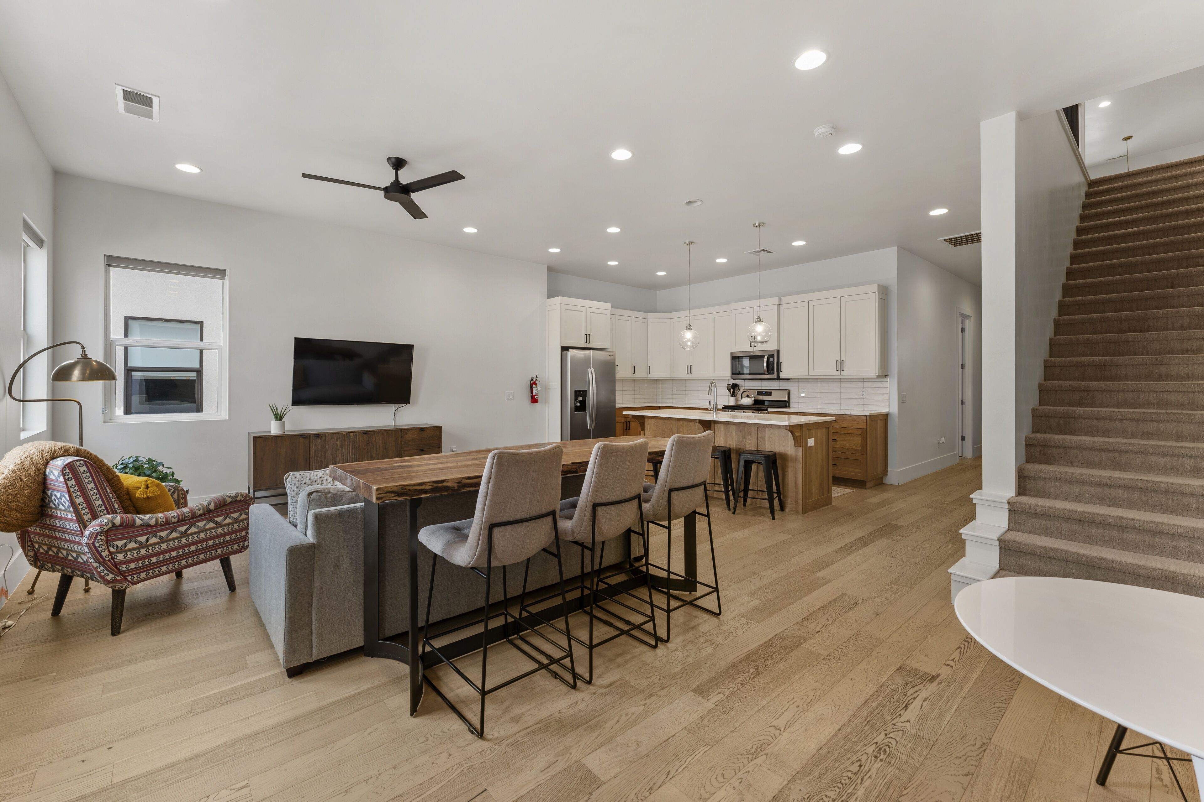 A modern kitchen with a central island, bar stools, and a dining table.